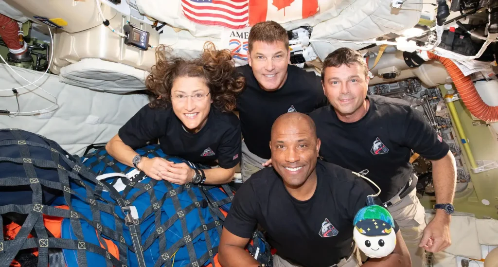 La tripulación de Artemis II – (de izquierda a derecha, en el sentido de las agujas del reloj) la Especialista de Misión Christina Koch, el Especialista de Misión Jeremy Hansen, el Comandante Reid Wiseman y el Piloto Victor Glover – posan para una foto grupal con su indicador de gravedad cero “Rise”, dentro de la nave Orión durante su regreso a la Tierra. Tras sobrevolar el lado lejano de la Luna el 6 de abril de 2026, la tripulación salió de la esfera de influencia lunar (el punto en que la gravedad de la Luna supera la de la Tierra sobre Orión) el 7 de abril y se dirige de regreso a la Tierra para un amerizaje en el Océano Pacífico el 10 de abril. Credit: NASA