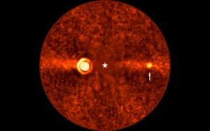 Esta imagen, obtenida con el Very Large Telescope (VLT) de ESO, muestra a Beta Pictoris d, un nuevo planeta que orbita la estrella Beta Pictoris. La estrella está en el centro de la imagen y se restó su brillo al procesar los datos, revelando el entorno que la rodea. El nuevo planeta, indicado con una flecha, es el tercero que se encuentra alrededor de esta estrella. Los otros dos son Beta Pictoris b (la fuente brillante a la izquierda), y Beta Pictoris c, orbitando mucho más cerca de la estrella y que en esta imagen no se ve.